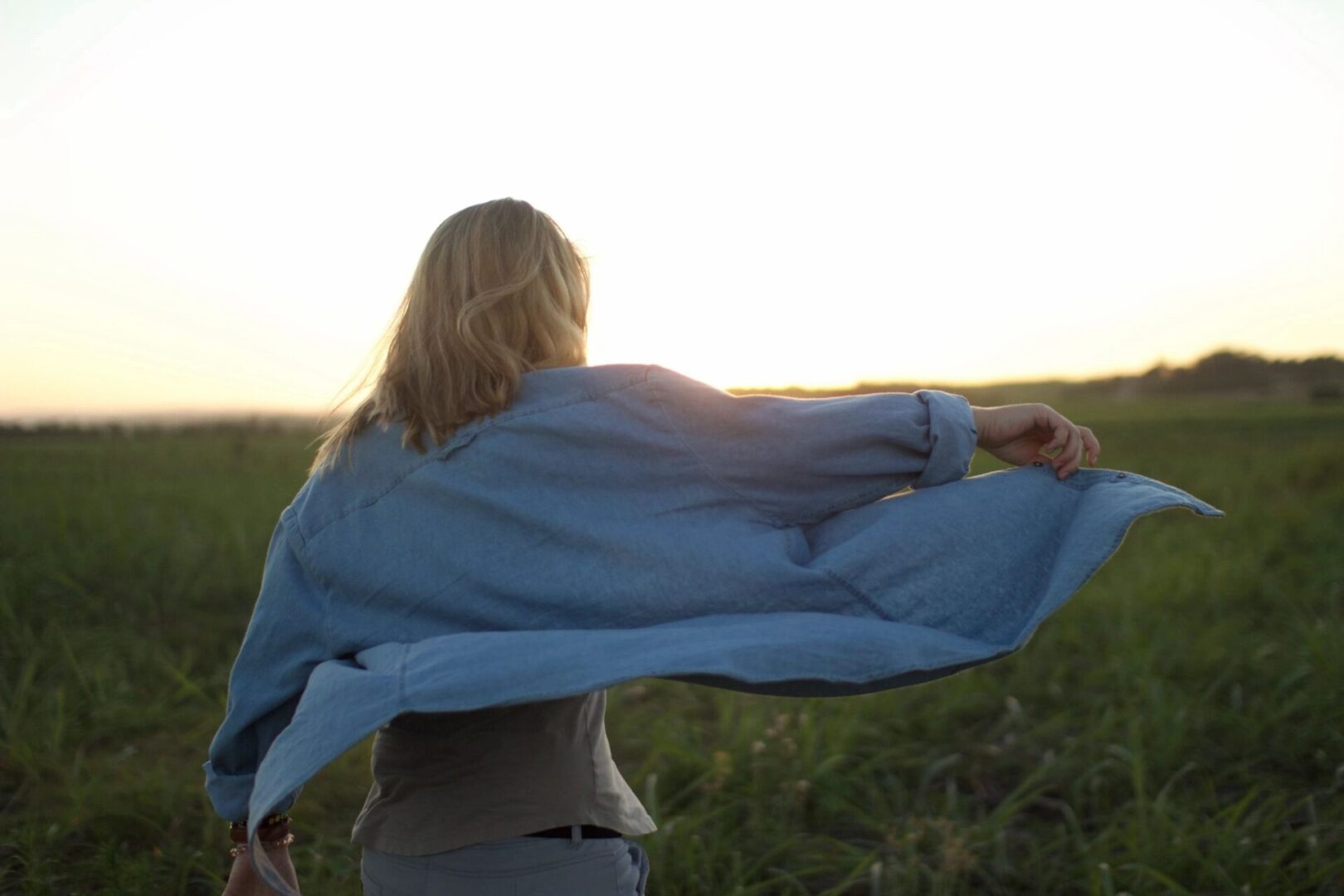 A woman in the grass holding onto her shirt