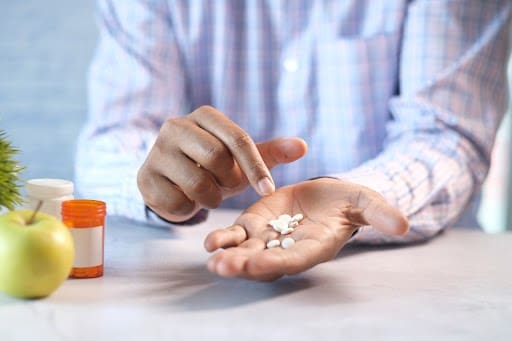 A person holding pills in their hands.